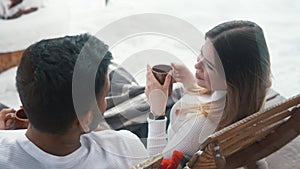 Happy young couple drinking hot chocolate while sitting on the bench outdoors on Valentines day