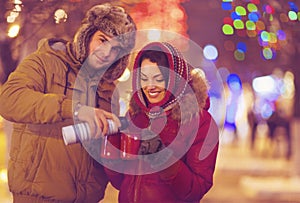 Happy young couple drinking tea on blurred lights background