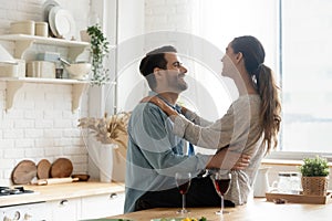 Happy young couple drinking wine talking bonding in modern kitchen