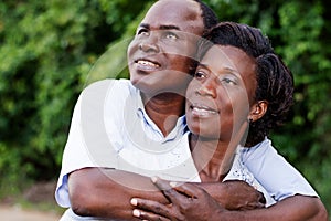 Happy young couple embracing looking in the same direction.