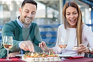 Happy young couple enjoying appetizers and drinking rose wine before lunch