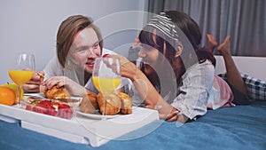 Happy young couple enjoying breakfast in bed. Sharing strawberries