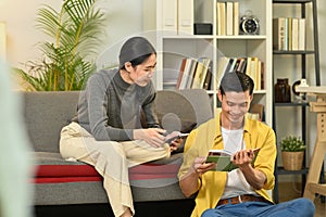 Happy young couple enjoying carefree leisure weekend time, reading book in cozy living room