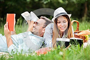 Happy young couple enjoying a good read during picnic in a park