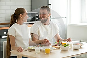 Happy young couple enjoying having breakfast at home kitchen tab