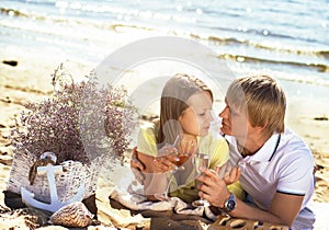 Happy young couple enjoying picnic on the beach and have good ti