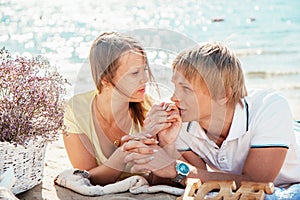 Happy young couple enjoying picnic on the beach and have good ti