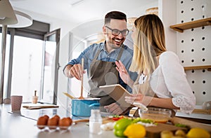 Happy young couple enjoys and having fun preparing healthy meal together at home kitchen.