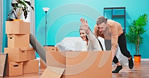 Happy young couple first time home buyers having fun unpacking laughing on moving day, excited