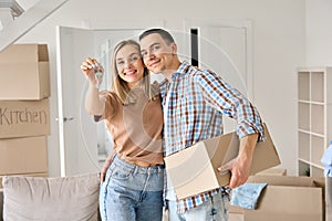 Happy young couple first time home owners holding keys in new home.