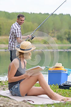 happy young couple fishing on lake