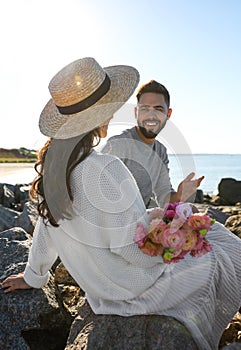 Happy young couple with flowers on beach. Honeymoon trip
