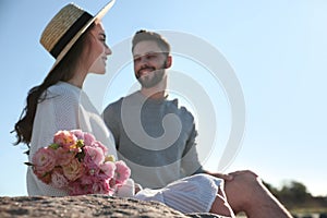 Happy young couple with flowers, focus on flowers. Honeymoon trip