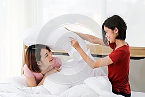 Happy young couple friend beautiful asia women having a pillow fight in their bedroom