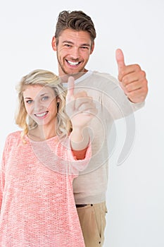 Happy young couple gesturing thumbs up