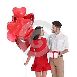Happy young couple with gift box and heart shaped balloons isolated. Valentine`s day celebration