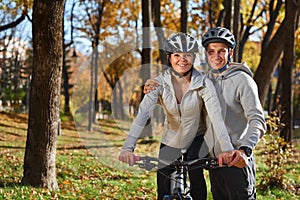 Happy young couple going for a bike ride on an autumn day in the park.