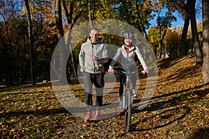 Happy young couple going for a bike ride on an autumn day in the park.