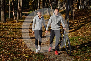 Happy young couple going for a bike ride on an autumn day in the park.