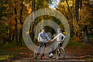 Happy young couple going for a bike ride on an autumn day in the park.