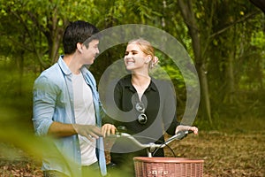 Happy young couple going for a bike ride on a sunny day in the park