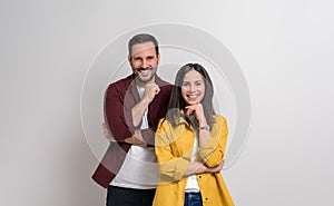 Happy young couple with hands on chins smiling at camera while posing on isolated white background