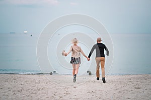 Happy young couple have fun on the beach, holding hands.