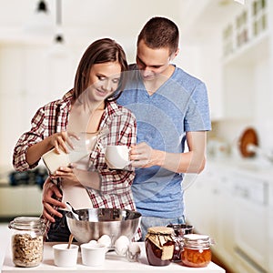 Happy young couple have fun in modern wooden kitchen indoor while preparing fresh food
