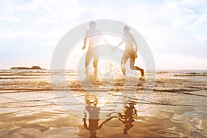 Happy young couple having fun on the beach at sunset, water splash photo