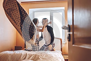 Happy young couple is having fun in bed in new empty home. Enjoying the company of each other. Pillow battle. Valentine`s Day