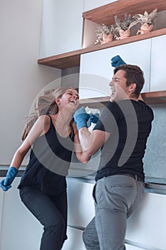 Happy young couple having fun while cleaning their kitchen .