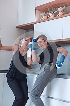 Happy young couple having fun while cleaning their kitchen .