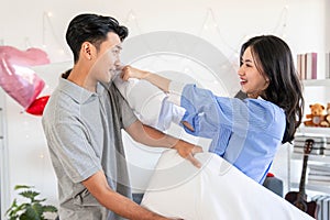 Happy young couple having fun pillow fight in bedroom Valentine day