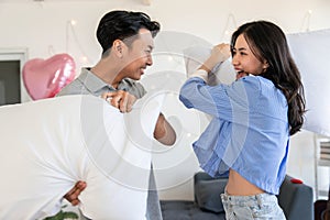 Happy young couple having fun pillow fight in bedroom Valentine day