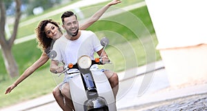 Young couple riding motor scooter in city