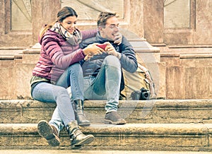 Happy young couple having fun with smartphone outdoors