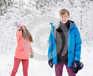 Happy young couple having fun together in snow in winter woodland