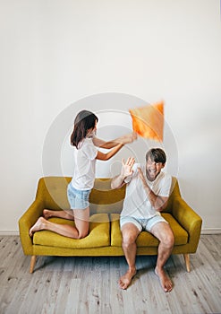 Happy young couple having fun. Woman beating scared boyfriend wi