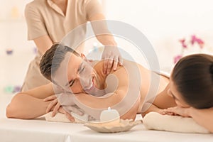 Happy young couple having massage in spa salon