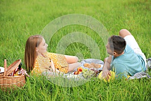 Happy young couple having picnic on grass in park