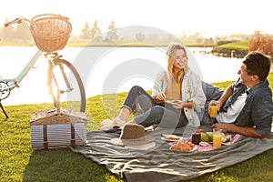 Happy young couple having picnic near lake