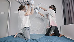 Happy young couple having pillows fight in the bedroom. Love and affection concept