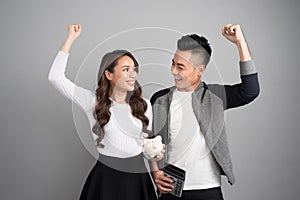 Happy young couple hold pink pig bank and calculator