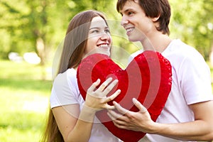Happy young couple holding big red heart