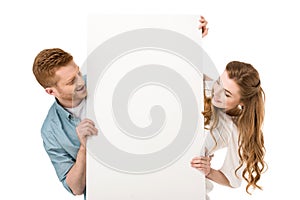 happy young couple holding blank placard and looking at copy space