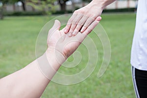 happy young couple holding hands in garden. Boyfriend and girlfriend walking in public park. Love, romance and relationship