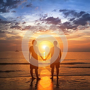 Happy young couple holding hands on sea beach during the beautiful sunset.