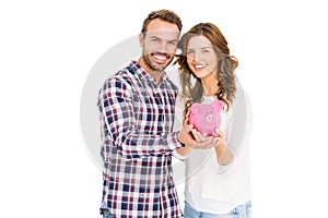 Happy young couple holding piggy bank