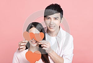 Happy young couple  holding red paper hearts  and celebrating  valentines day