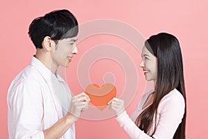 Happy young couple  holding red paper hearts  and celebrating  valentines day